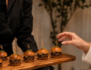 A server presenting a board of mini sliders