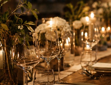 A candlelit long table set with plates and glasses