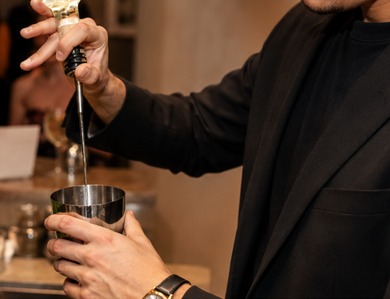 A host mixing a drink at the counter while guests look on